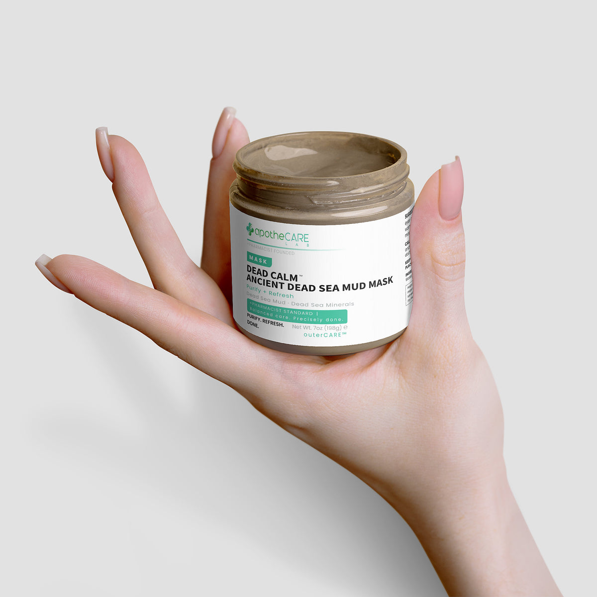Hand holding a jar of skincare product against a plain background
