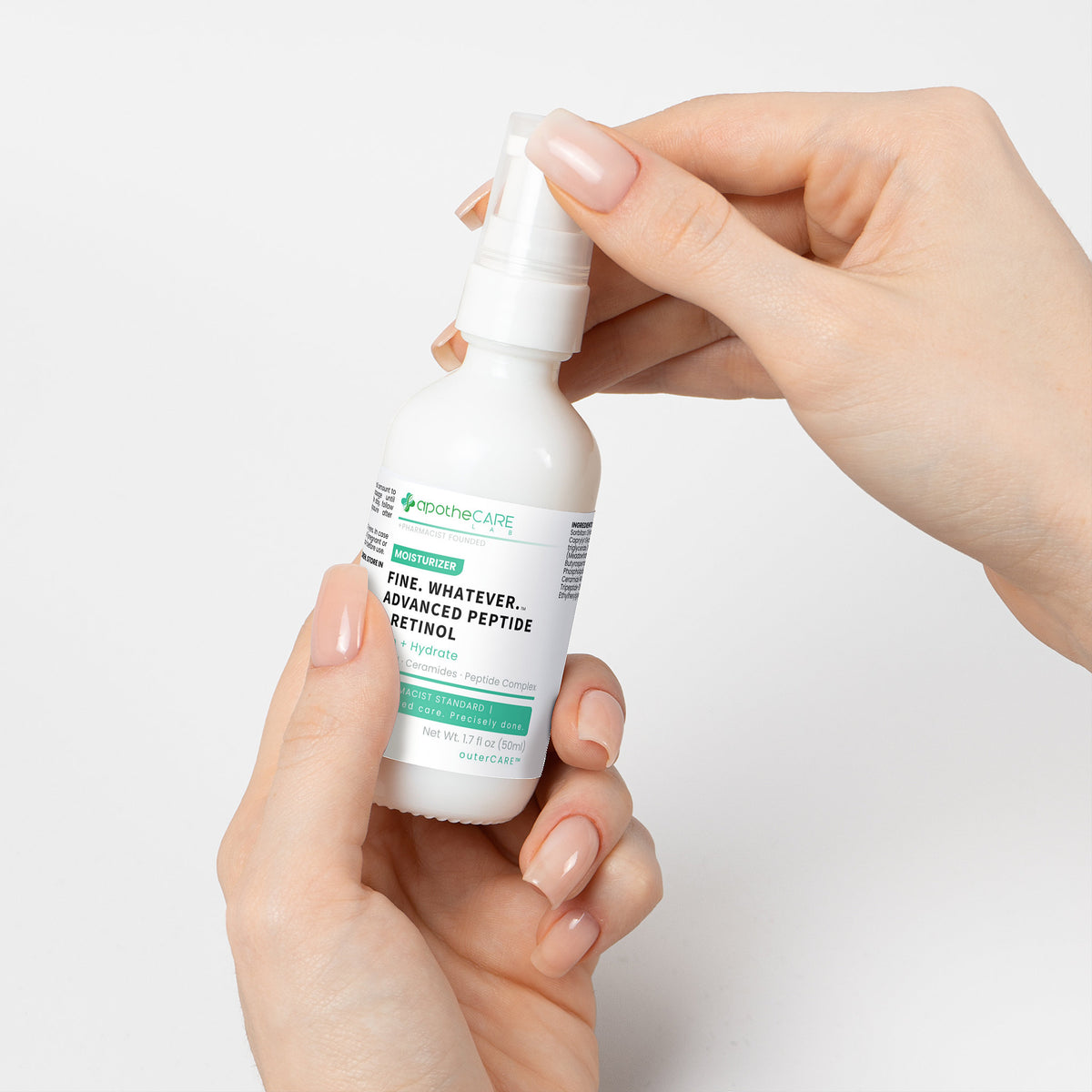 Hand holding a white bottle with a label against a light gray background