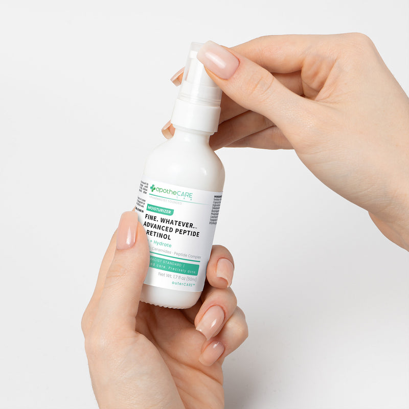 Hand holding a white bottle with a label against a light gray background