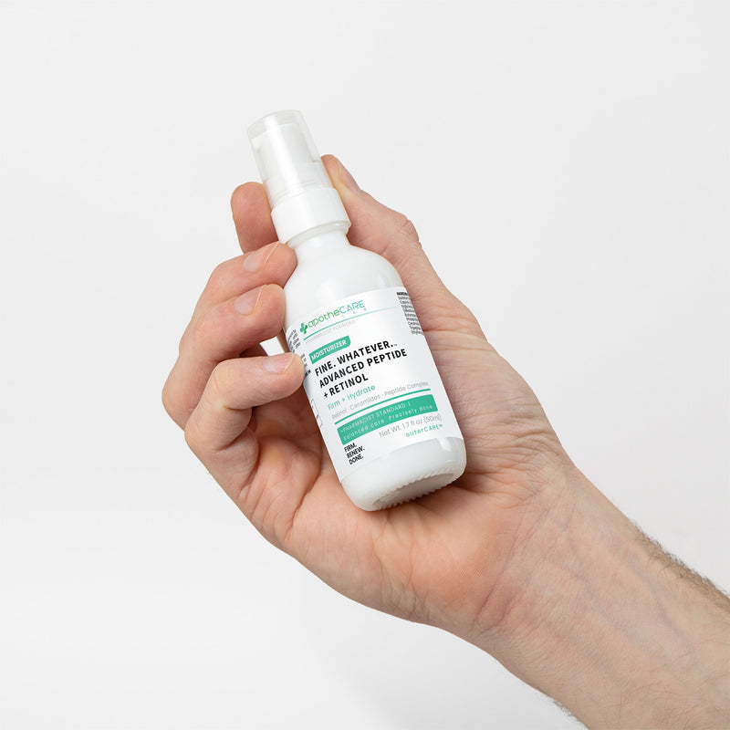 Hand holding a white spray bottle with a green label on a light gray background