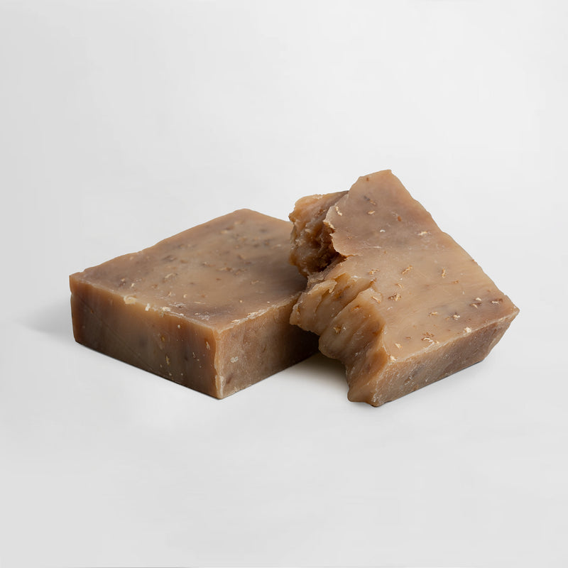 Two pieces of brown soap on a light gray background