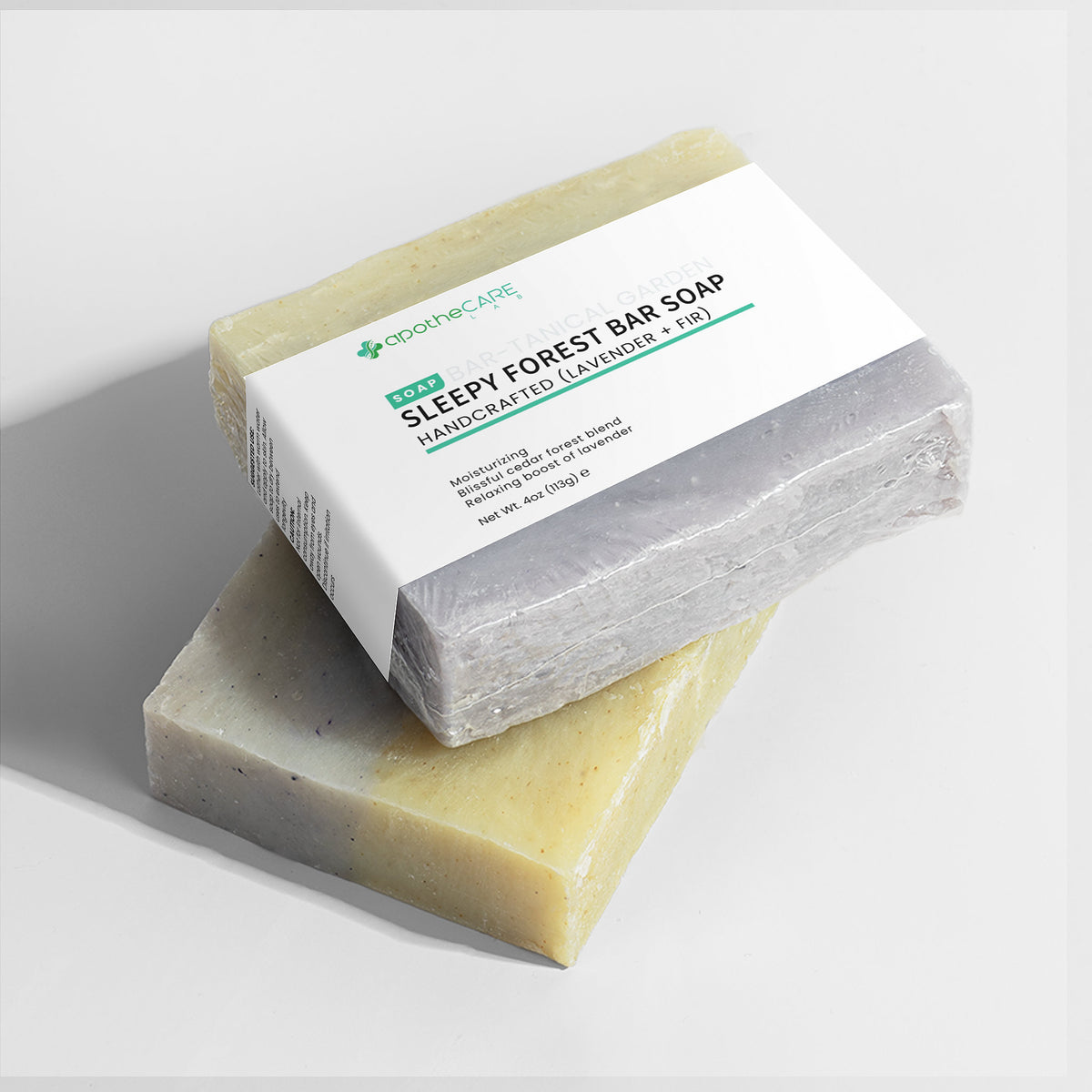 Two rectangular bars of soap stacked on a light gray background, with the top bar wrapped in a white paper label reading 'SLEEPY FOREST BAR SOAP HANDCRAFTED LAVENDER + FIR'.