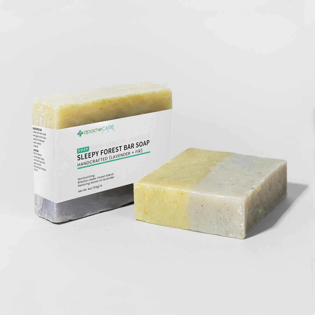 A handmade bar soap product shown with its paper packaging on a clean white studio background. The soap bar has a two-tone color identity of pale yellow and off-white with tiny speckles, and the label reads 'SLEEPY FOREST BAR SOAP'.