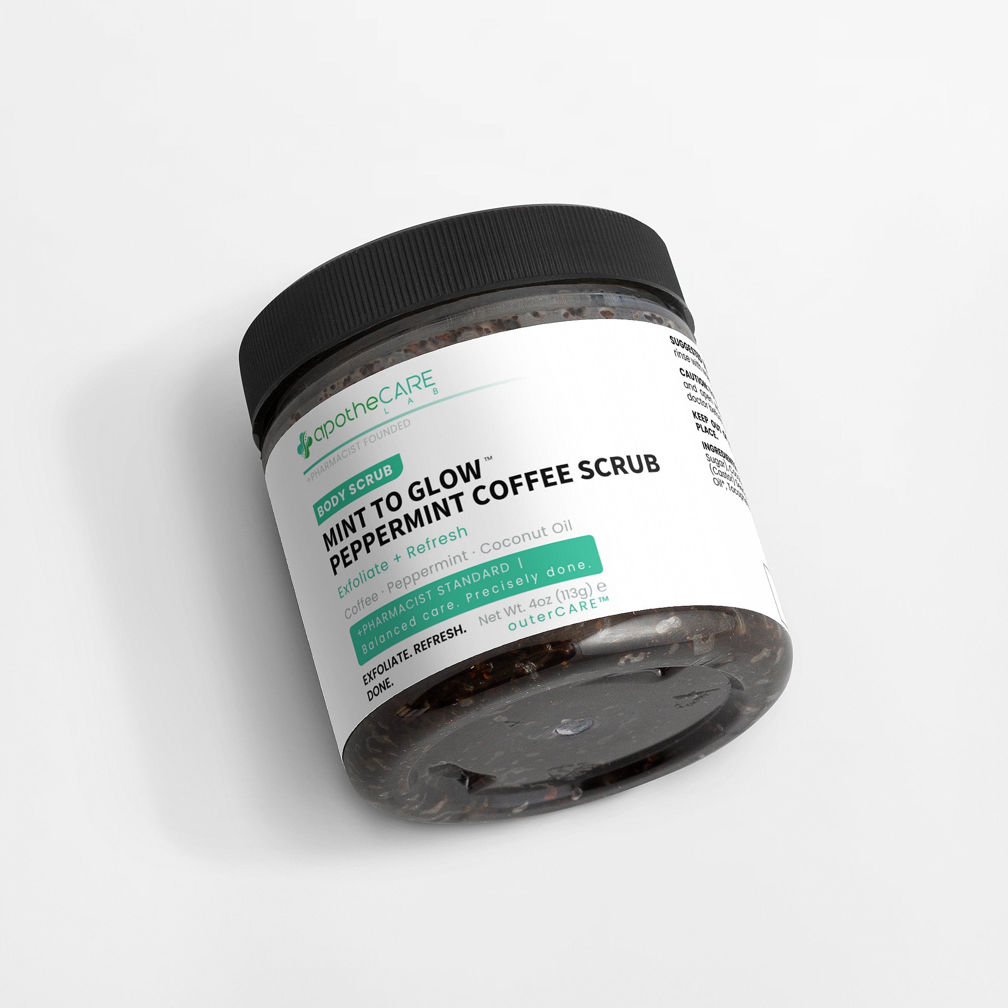 A jar of apotheCARE Mint to Glow Peppermint Coffee Scrub, featuring a black lid and a white label with green and black text, set against a clean white background.