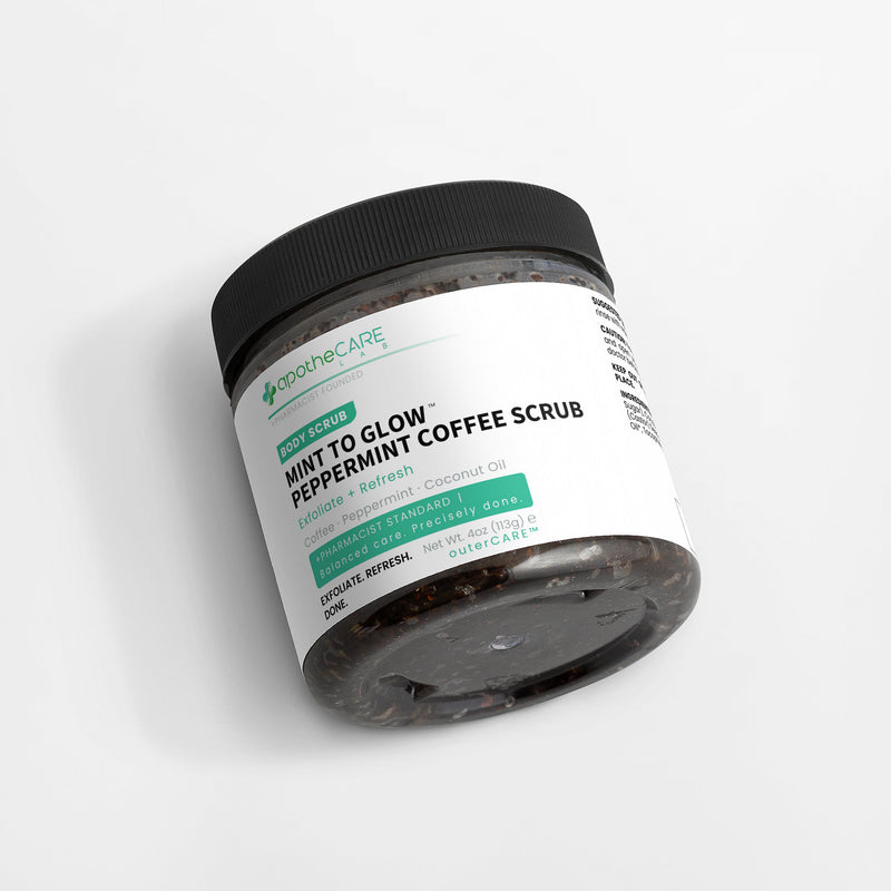 A jar of apotheCARE Mint to Glow Peppermint Coffee Scrub, featuring a black lid and a white label with green and black text, set against a clean white background.