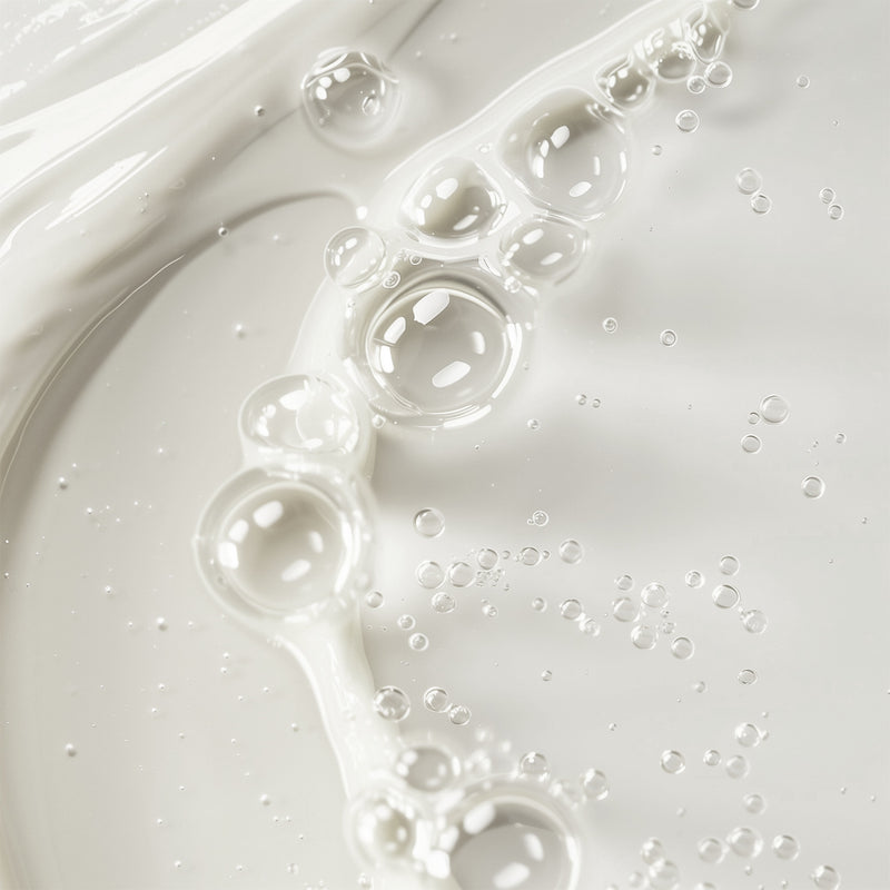 Close-up of white liquid with bubbles on a light gray background