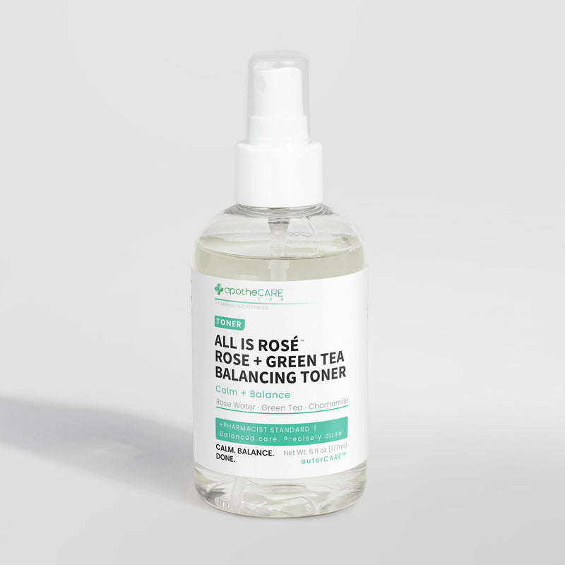 A clear plastic spray bottle of apotheCare All Is Rosé Rose + Green Tea Balancing Toner with a white pump dispenser and a white label, set against a light gray background.