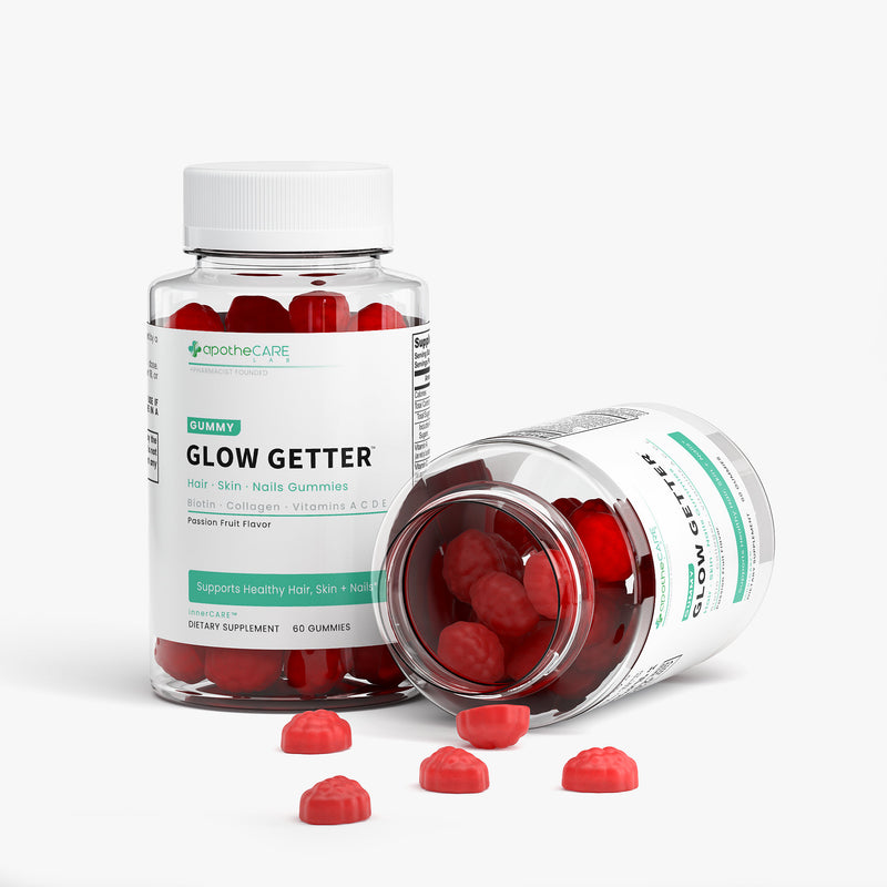 Two clear supplement bottles of apotheCARE LAB Glow Getter gummies with white caps, one standing upright and one lying on its side, with several red gummies scattered in front on a clean white background.