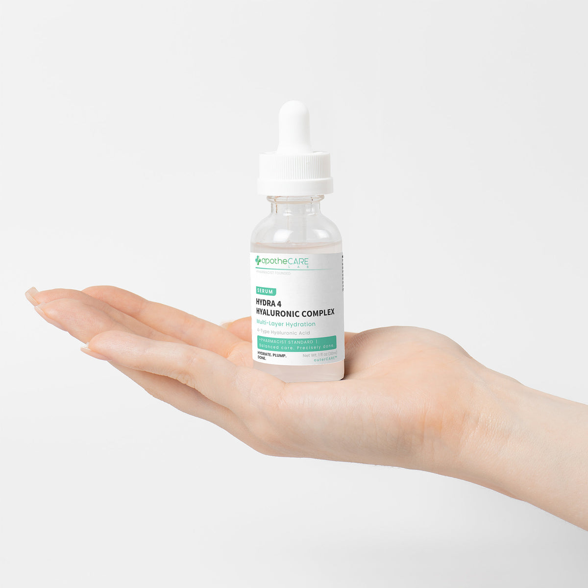 A clear dropper bottle of apotheCARE Lab Hydra-4 Hyaluronic Complex serum held in a person's open hand against a clean white background.