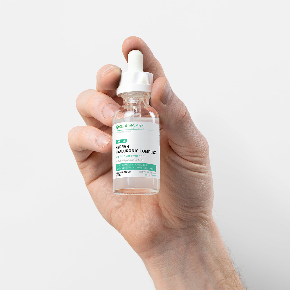 A hand holding a small glass dropper bottle of apotheCARE LAB Hydra 4 - Hyaluronic Complex serum against a clean white background.