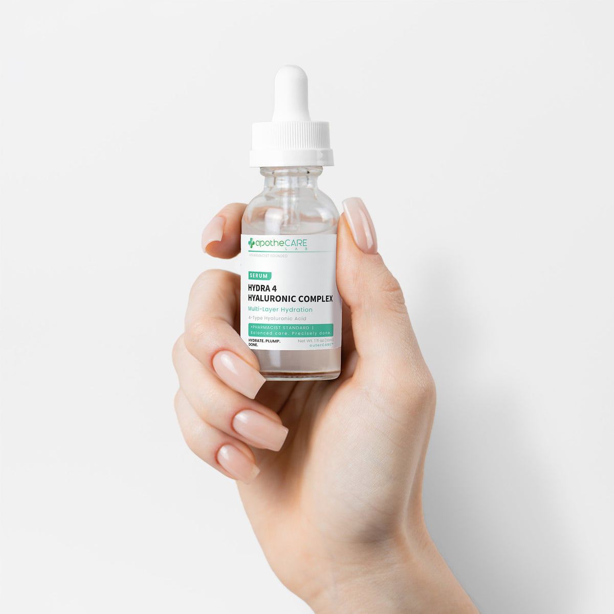 A hand holding a clear dropper bottle of apotheCARE Hydra-4 Hyaluronic Complex serum against a clean white background.