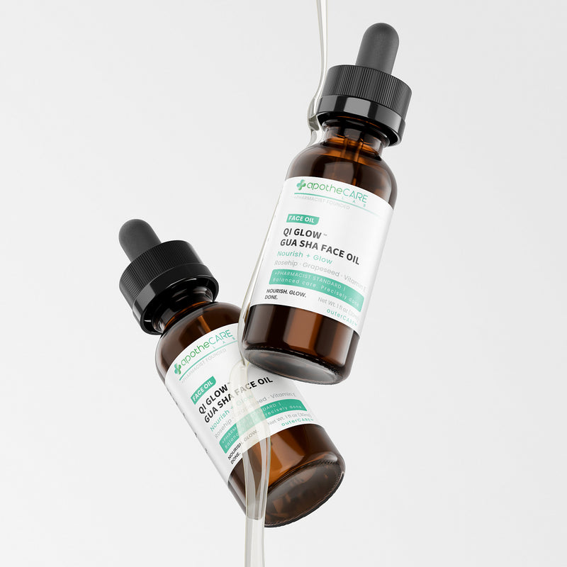 Two amber glass dropper bottles of Apothecare Lab QI Glow Gua Sha Face Oil floating against a clean light gray background.