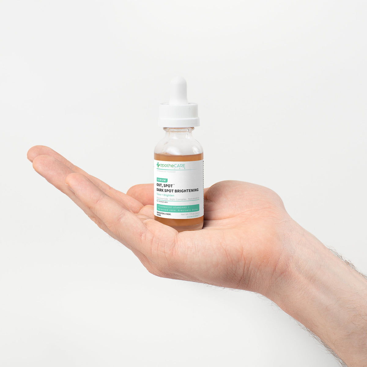 Hand holding a bottle of Out, Spot. Dark Spot Serum against a white background