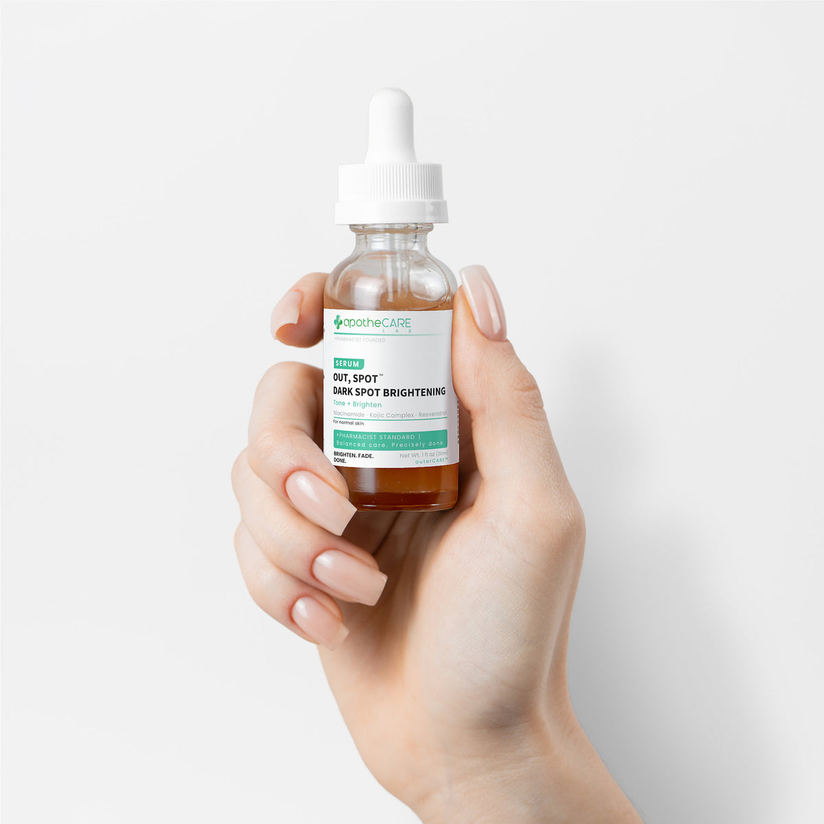 Hand holding a bottle of 'Out, Spot. Dark Spot Serum' against a light background