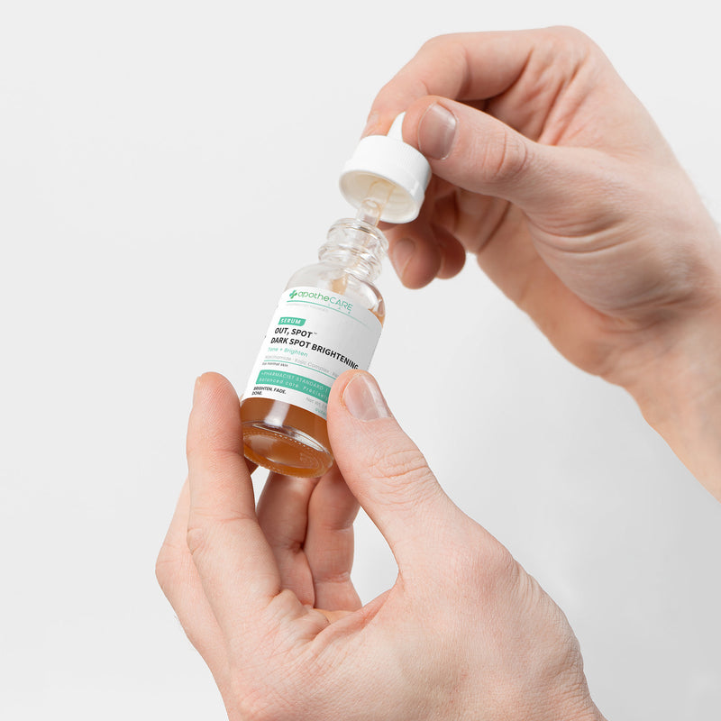 Hand holding a bottle of 'Out, Spot.' dark spot serum with a dropper.