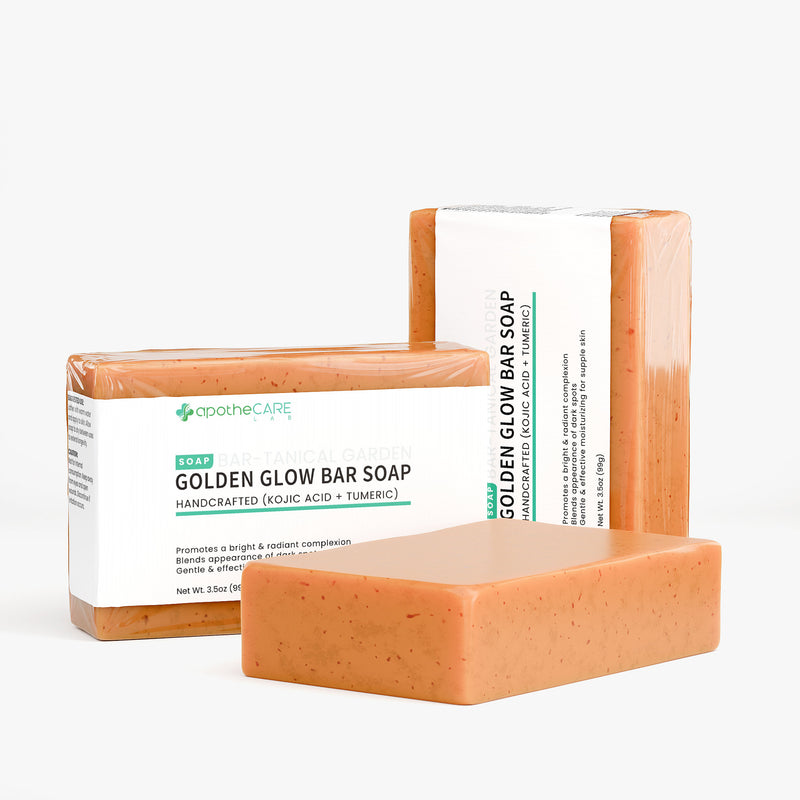Three bars of Apothcare Golden Glow Bar Soap are displayed against a clean, off-white background. One bar is in the foreground, while two are wrapped in clear plastic with white labels behind it.