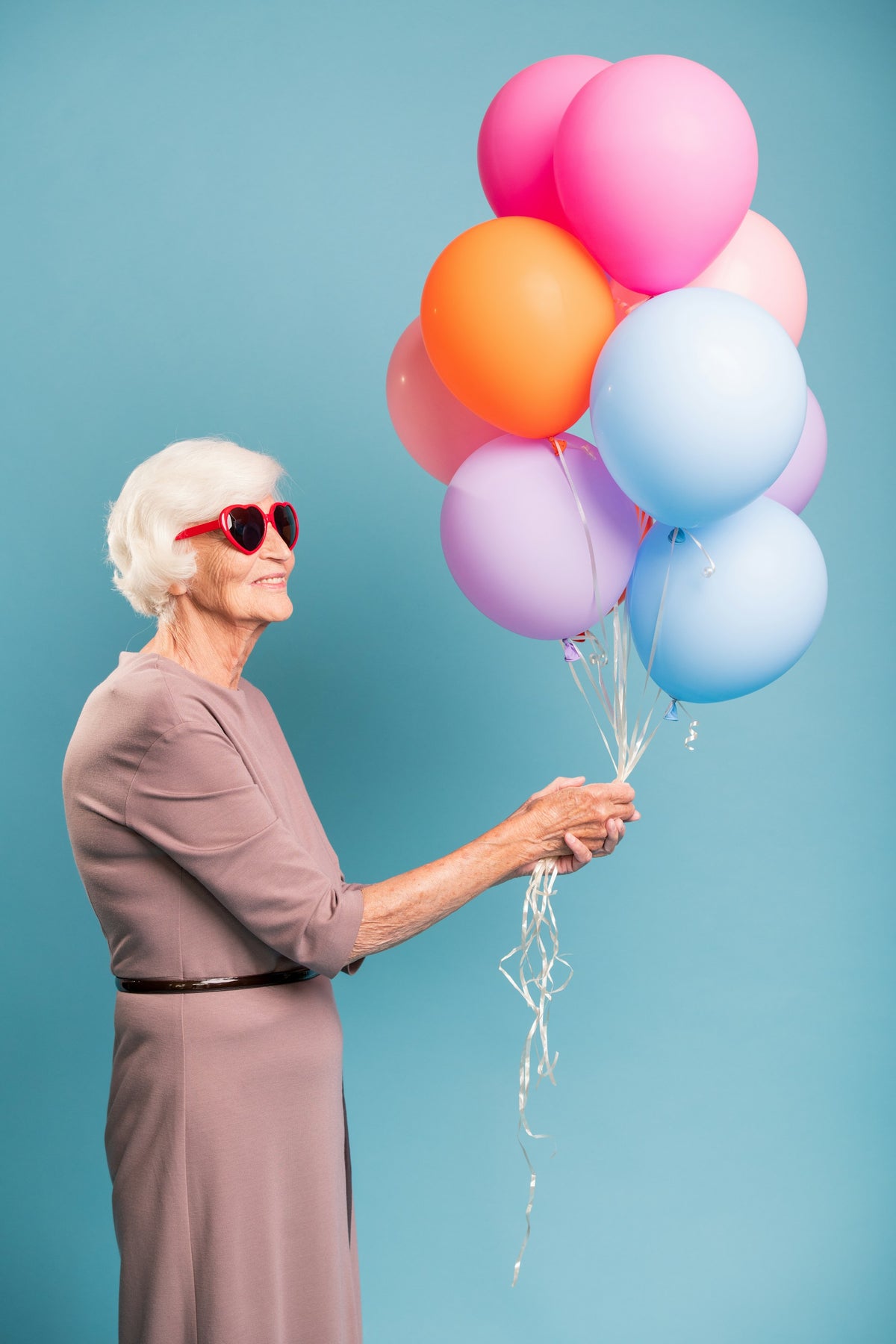 Woman holding colorful balloons against a blue background