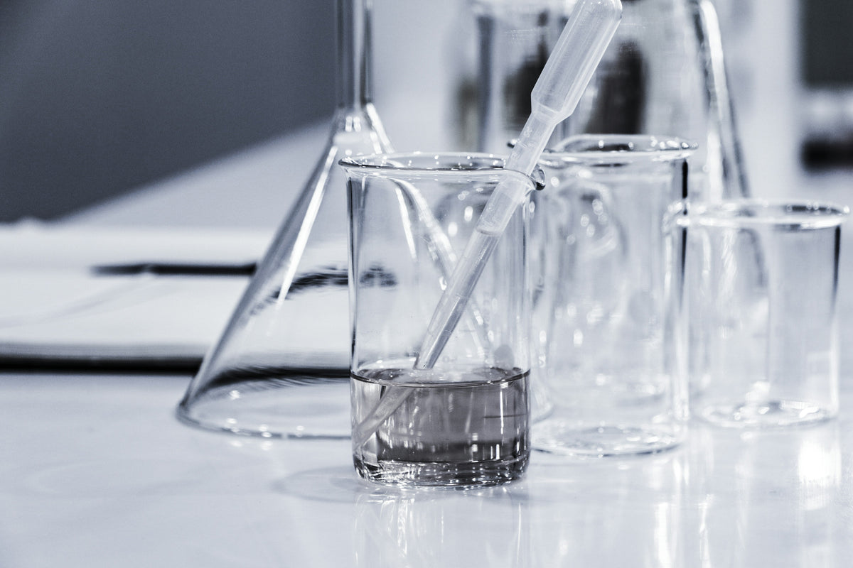 Close-up of a group of glass beakers, flasks, and jars on a white countertop.