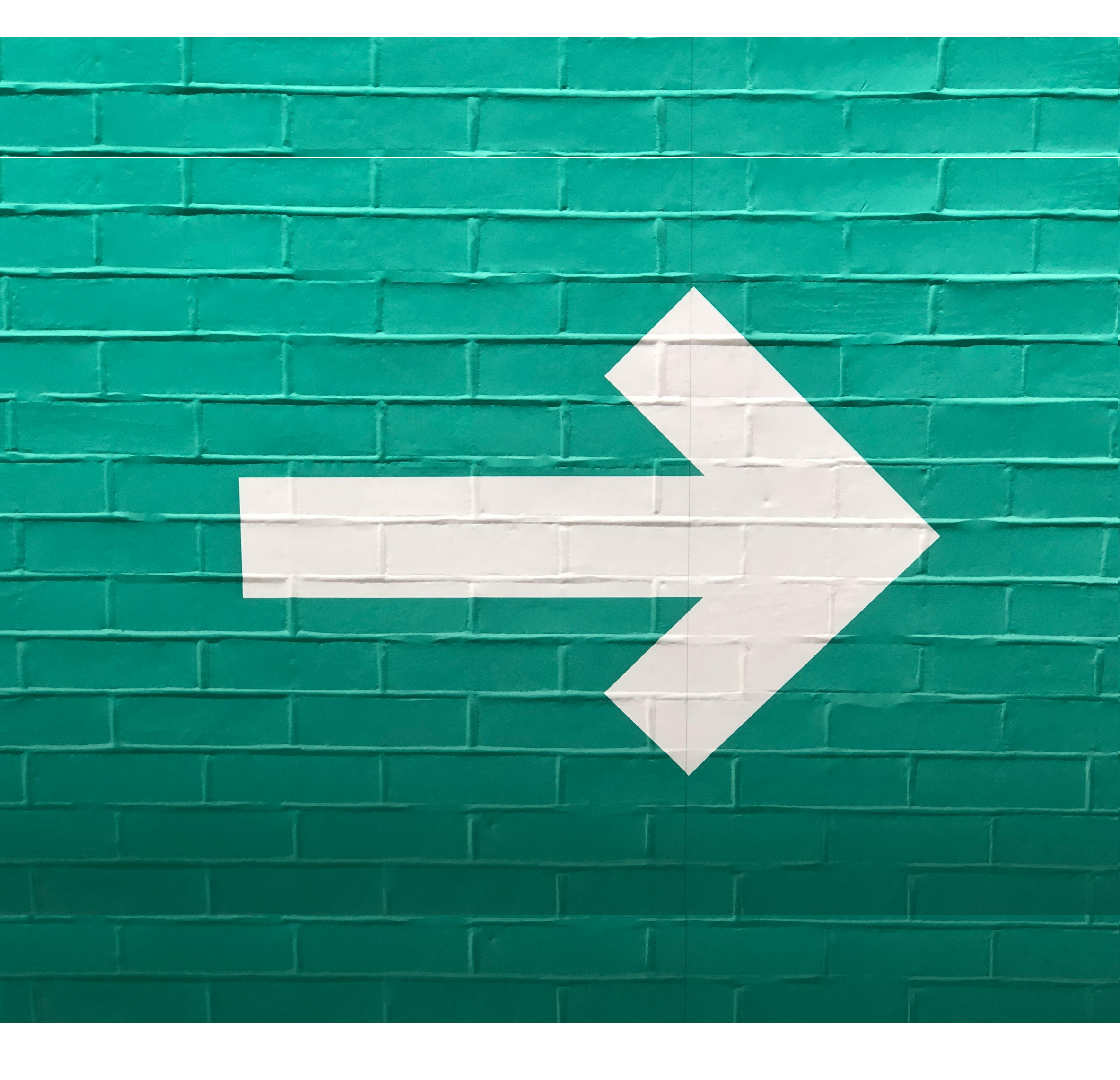 White arrow on a green brick wall
