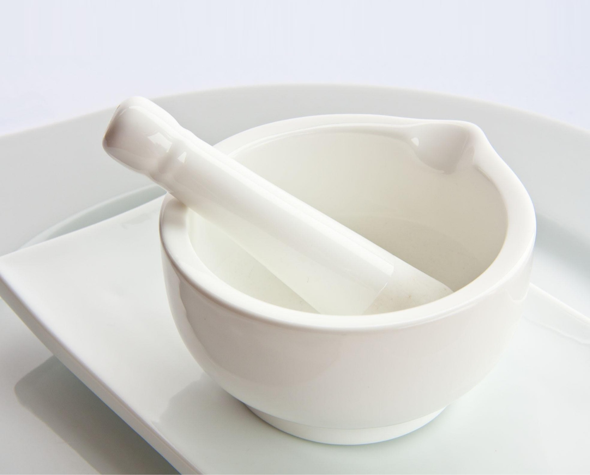 White ceramic mortar and pestle on a white surface