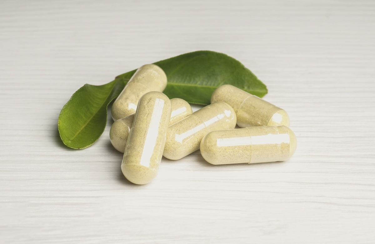 A few light yellow capsules on a green leaf over a tan white wooden table